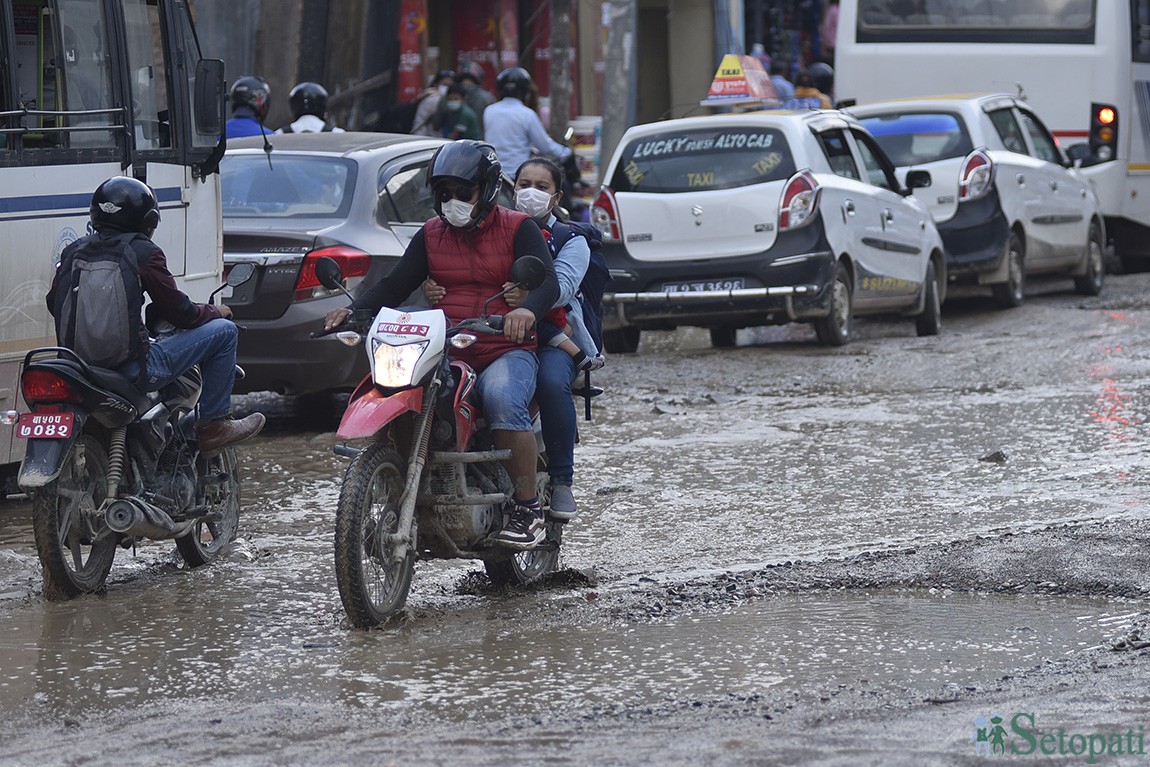 बौद्ध सडकमा टिलपिल जमेको हिलोमाथि ढलपल सवारी। यो सडक चार वर्षदेखि यस्तै जीर्ण र अस्तव्यस्त छ। तस्बिरहरूः नारायण महर्जन/सेतोपाटी